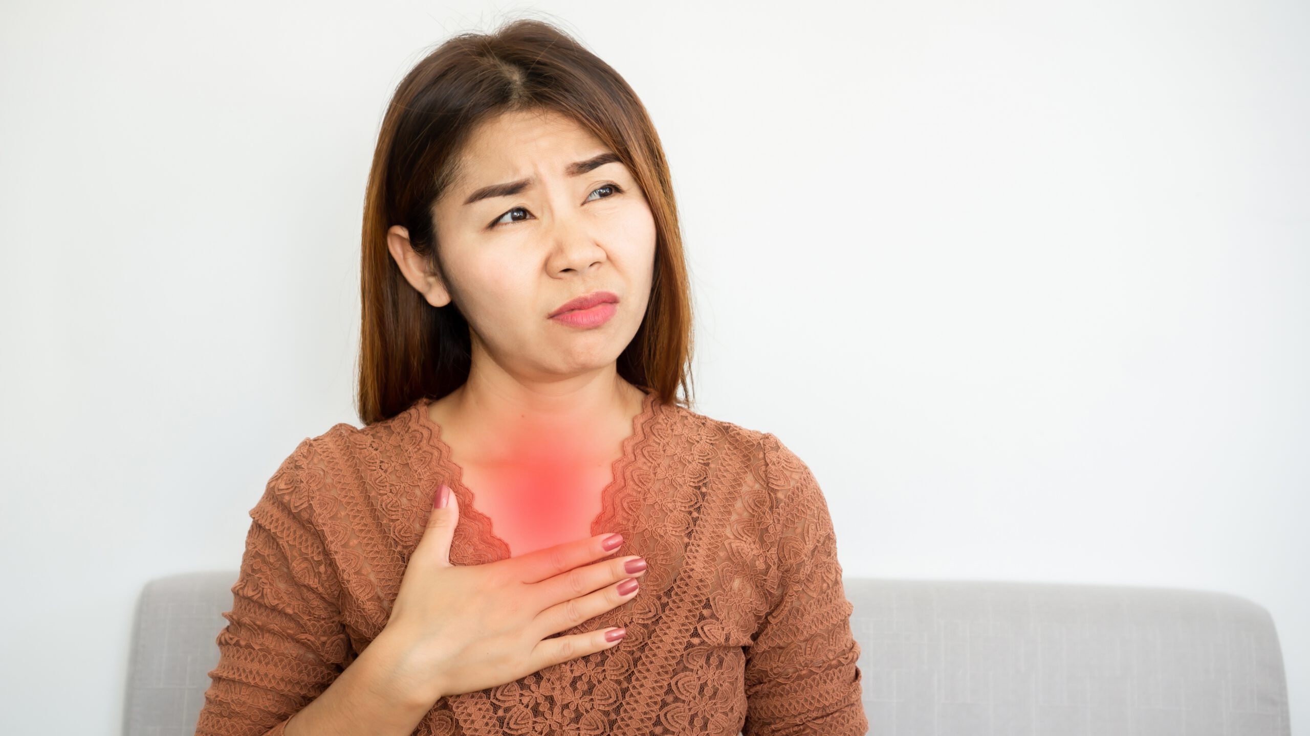 Woman experiencing chest discomfort due to acidity or gastric, pressing her chest with a concerned expression. The red highlight over her chest symbolizes internal burning sensation, commonly associated with hyperacidity or gastritis.