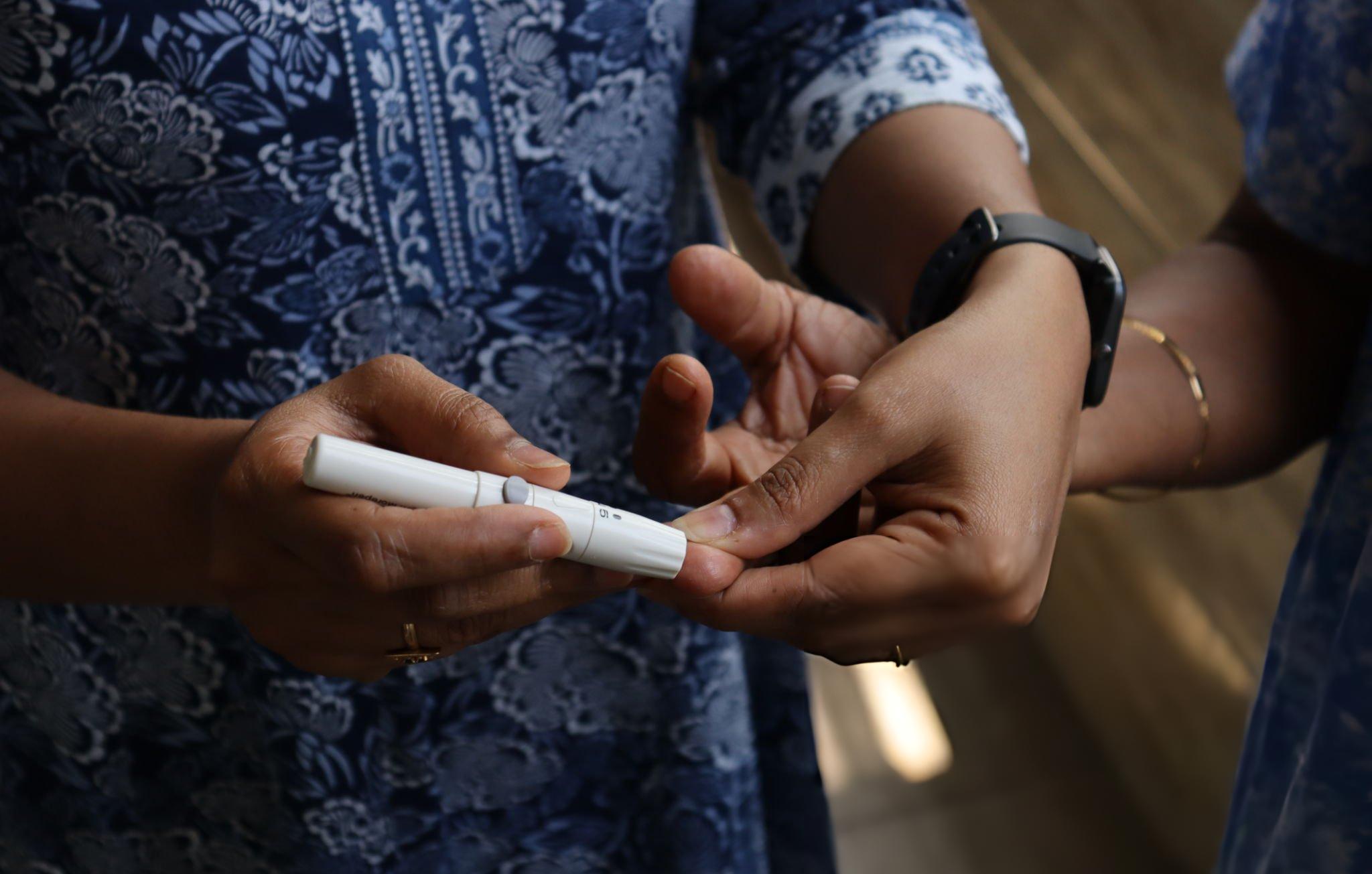 A person checking blood sugar with a lancet device as part of managing Type 2 Diabetes