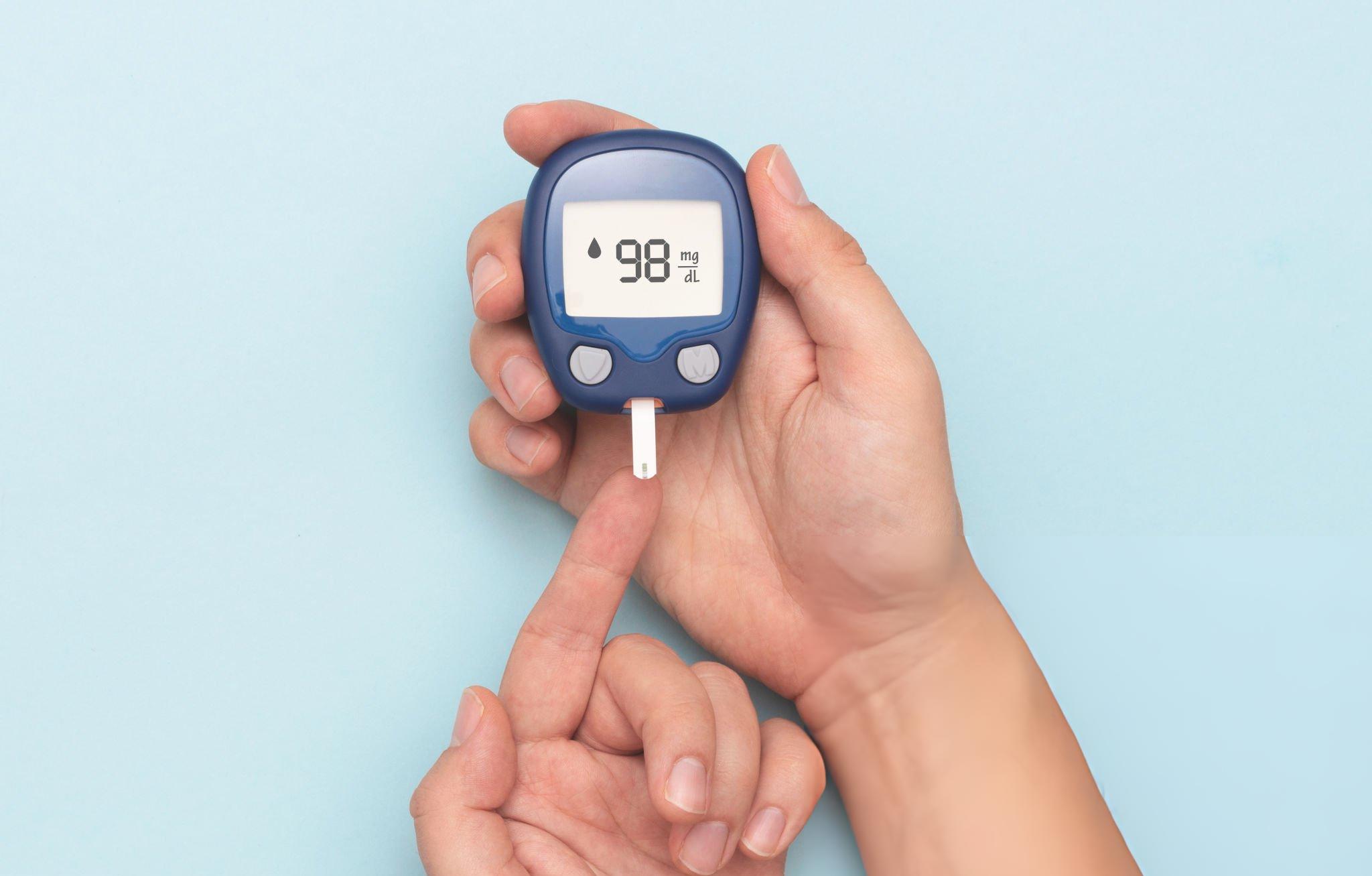 A person checking blood sugar levels with a glucometer, representing the latest treatment for type 2 diabetes and modern Ayurvedic approaches to managing blood glucose naturally.