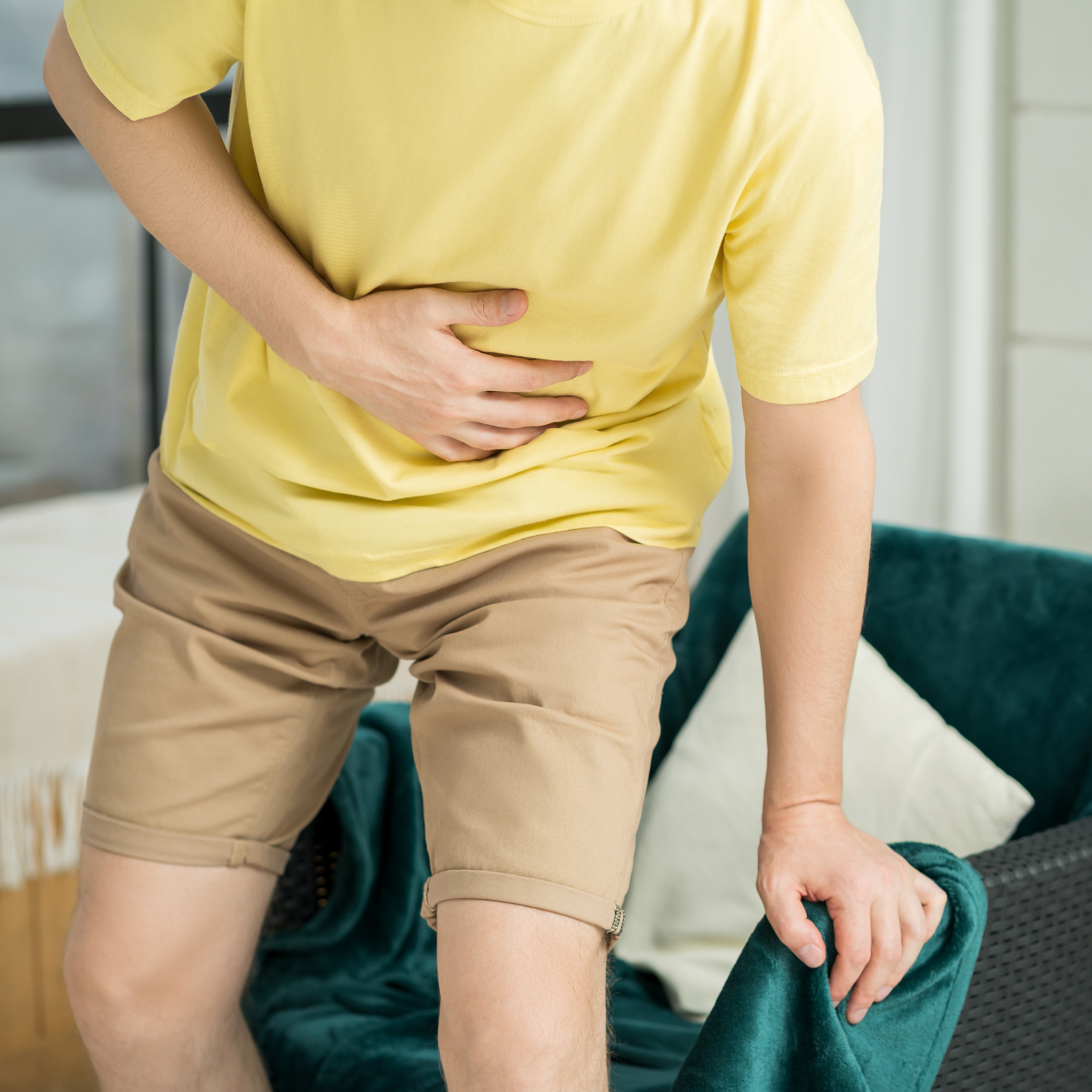 Person holding their abdomen in pain, showing discomfort from digestive issues related to ulcerative colitis.