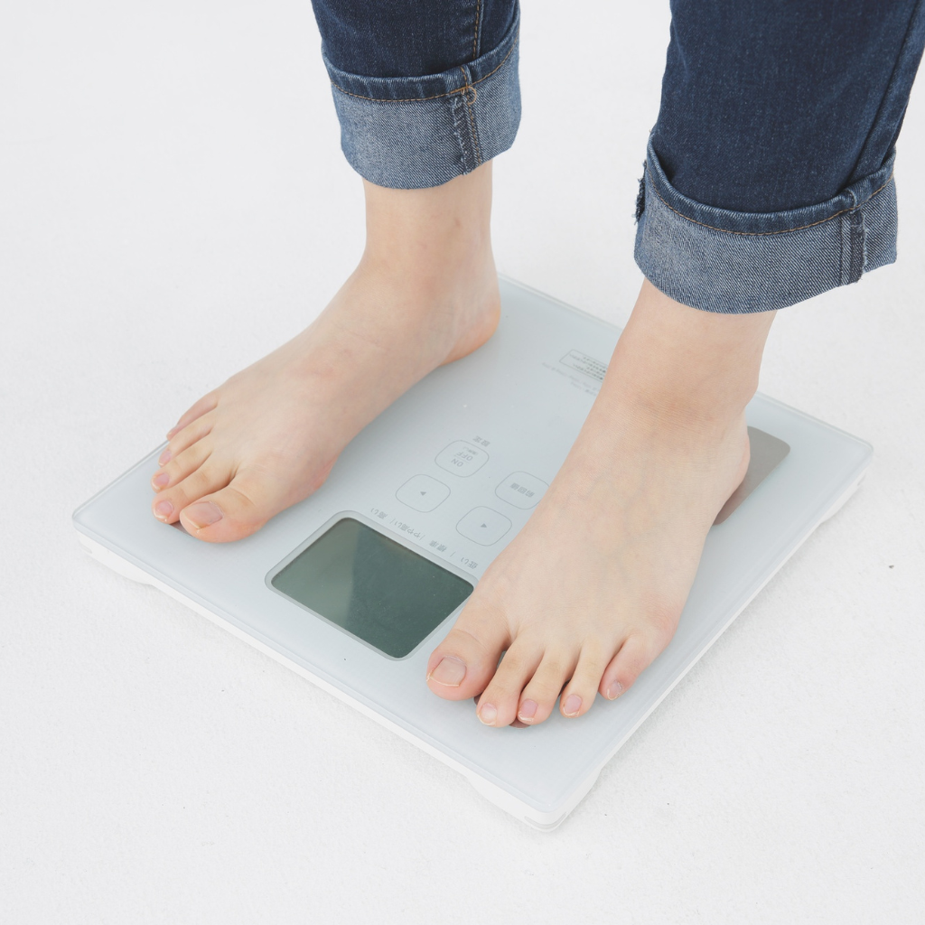 Person standing on a weighing scale representing the ayurvedic way to lose weight naturally and safely.