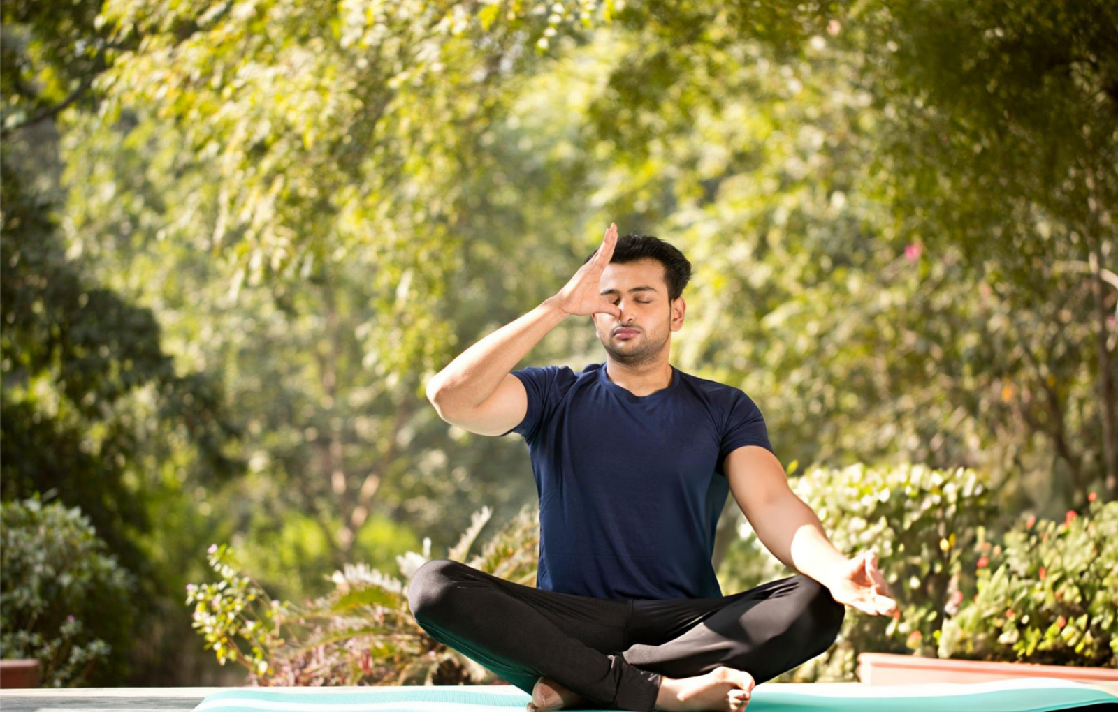 A man practicing Pranayama (alternate nostril breathing) in a peaceful outdoor garden, illustrating an effective Ayurvedic treatment for stress and anxiety through mindful breathing and meditation.
