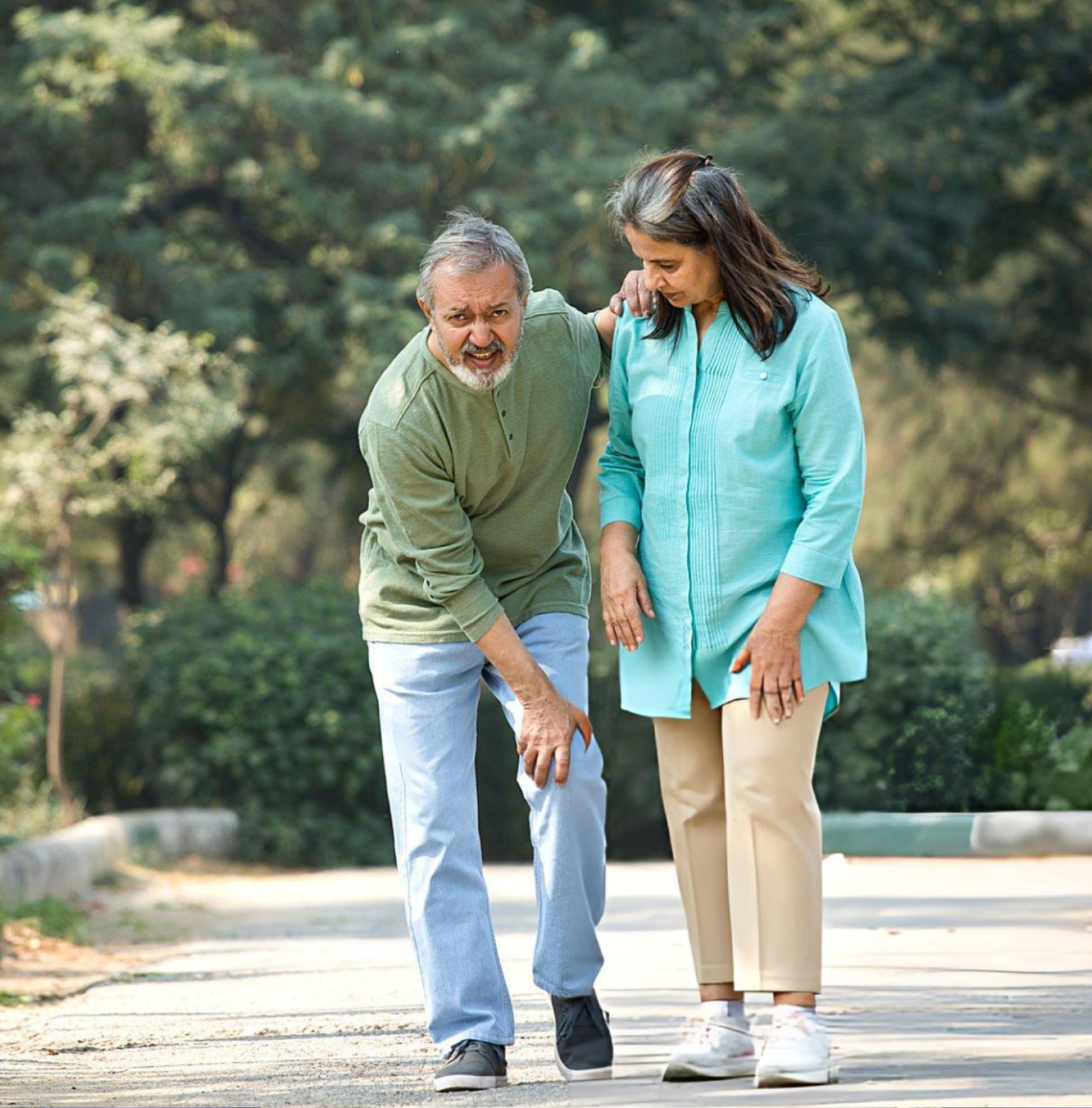 Elderly Indian man with knee joint pain supported by wife — seeking Joint Pain Ayurveda treatment