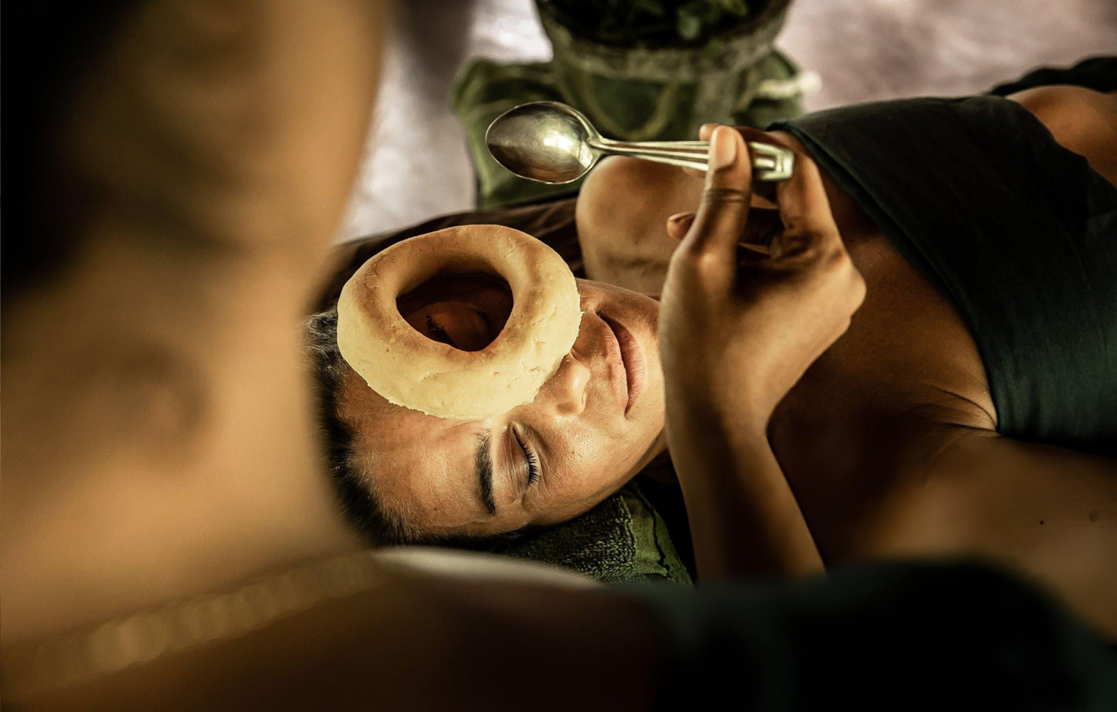 A woman receiving a traditional Ayurvedic Netra Tarpana eye therapy, where medicated ghee is gently applied around the eyes using a herbal dough ring, highlighting Ayurveda treatment for menopause and holistic wellness.