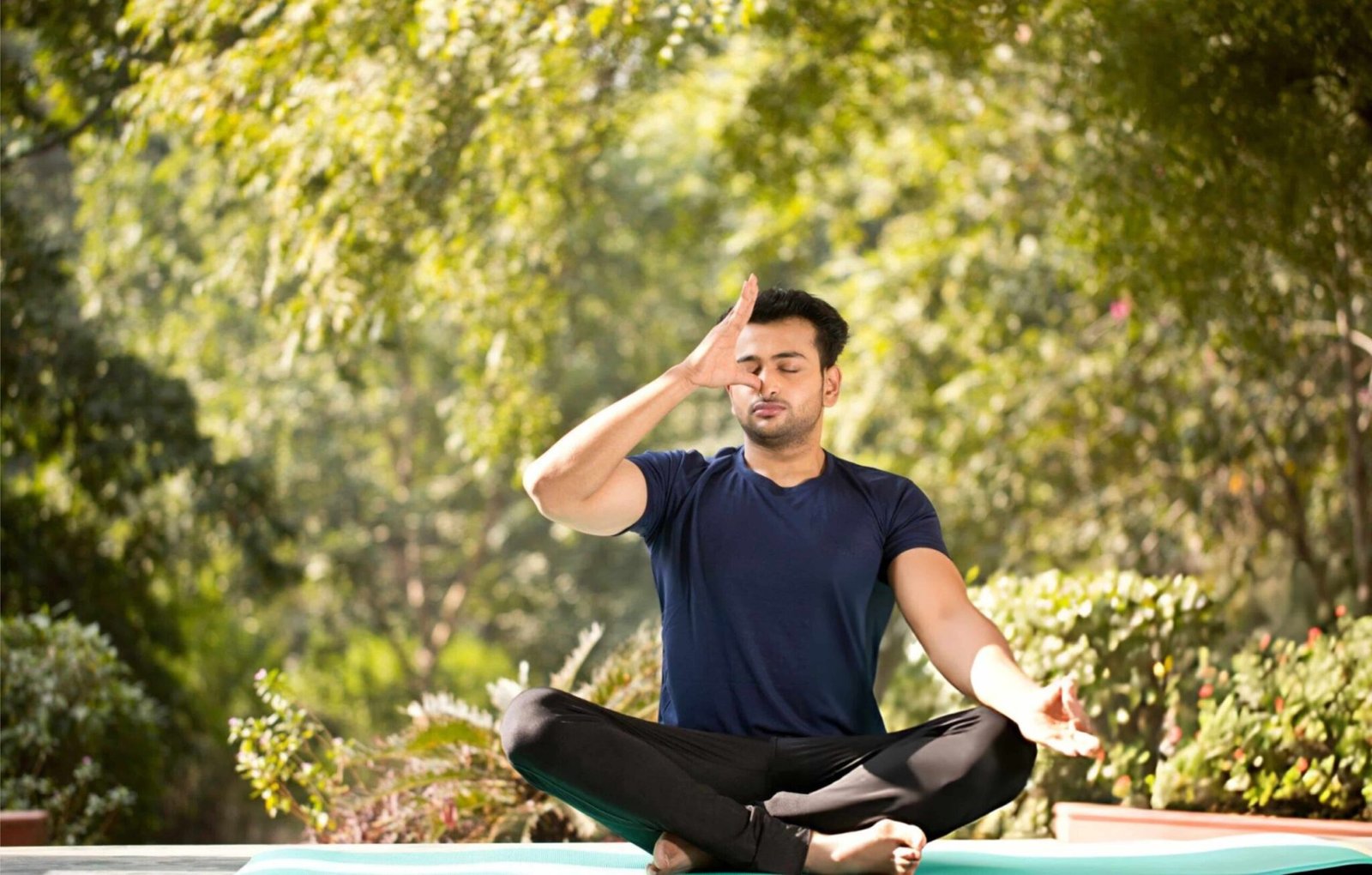 Man practicing Pranayama breathing meditation outdoors as part of Ayurvedic treatment for stress and anxiety to improve mental wellness.