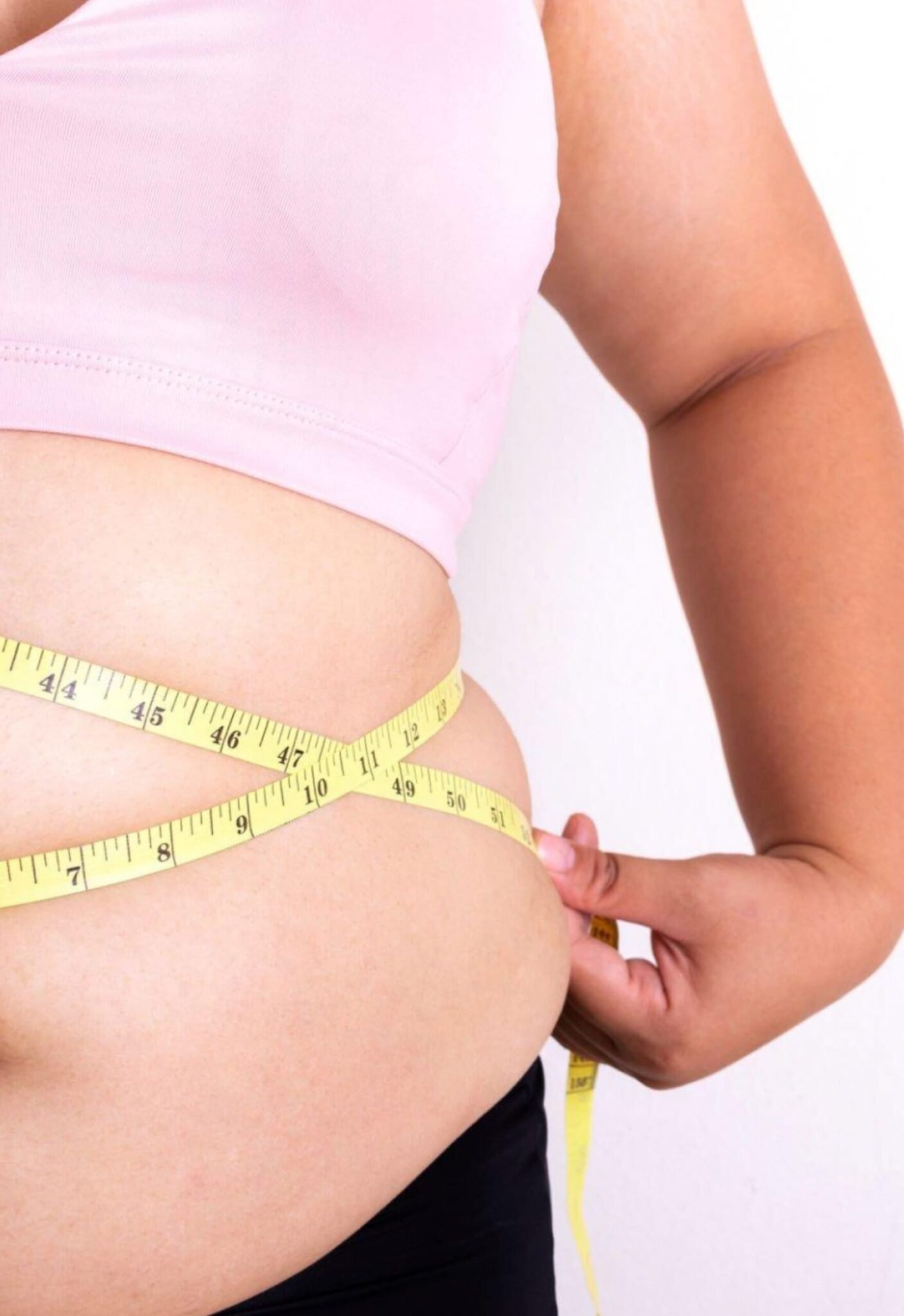Woman measuring her waist with a tape measure, highlighting natural body slimming and Ayurvedic weight loss treatment in Kerala.