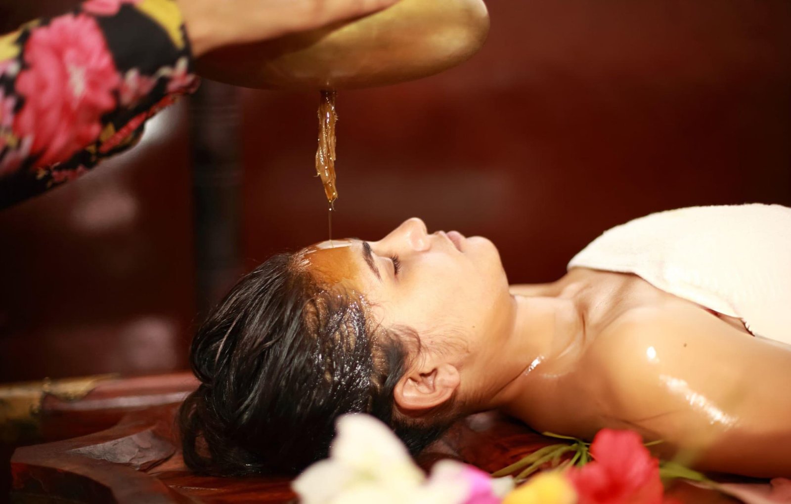 Woman receiving Shirodhara therapy at an Ayurvedic wellness center as part of an Ayurvedic Weight Loss Treatment in Kerala program.