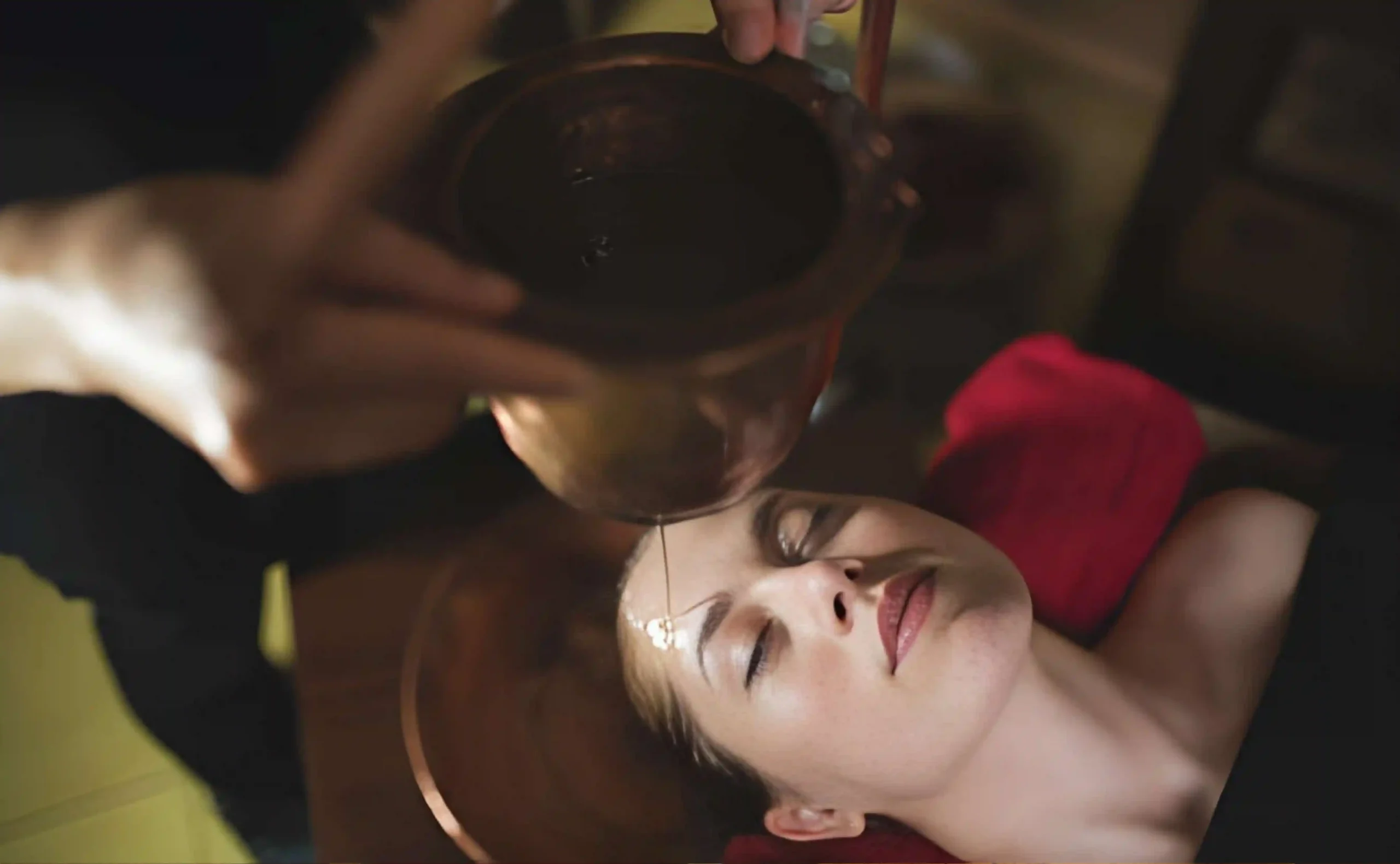 A woman undergoing an Ayurvedic Shirodhara therapy, where warm herbal oil is gently poured onto the forehead, symbolizing natural Ayurveda treatment for menopause and hormonal balance.