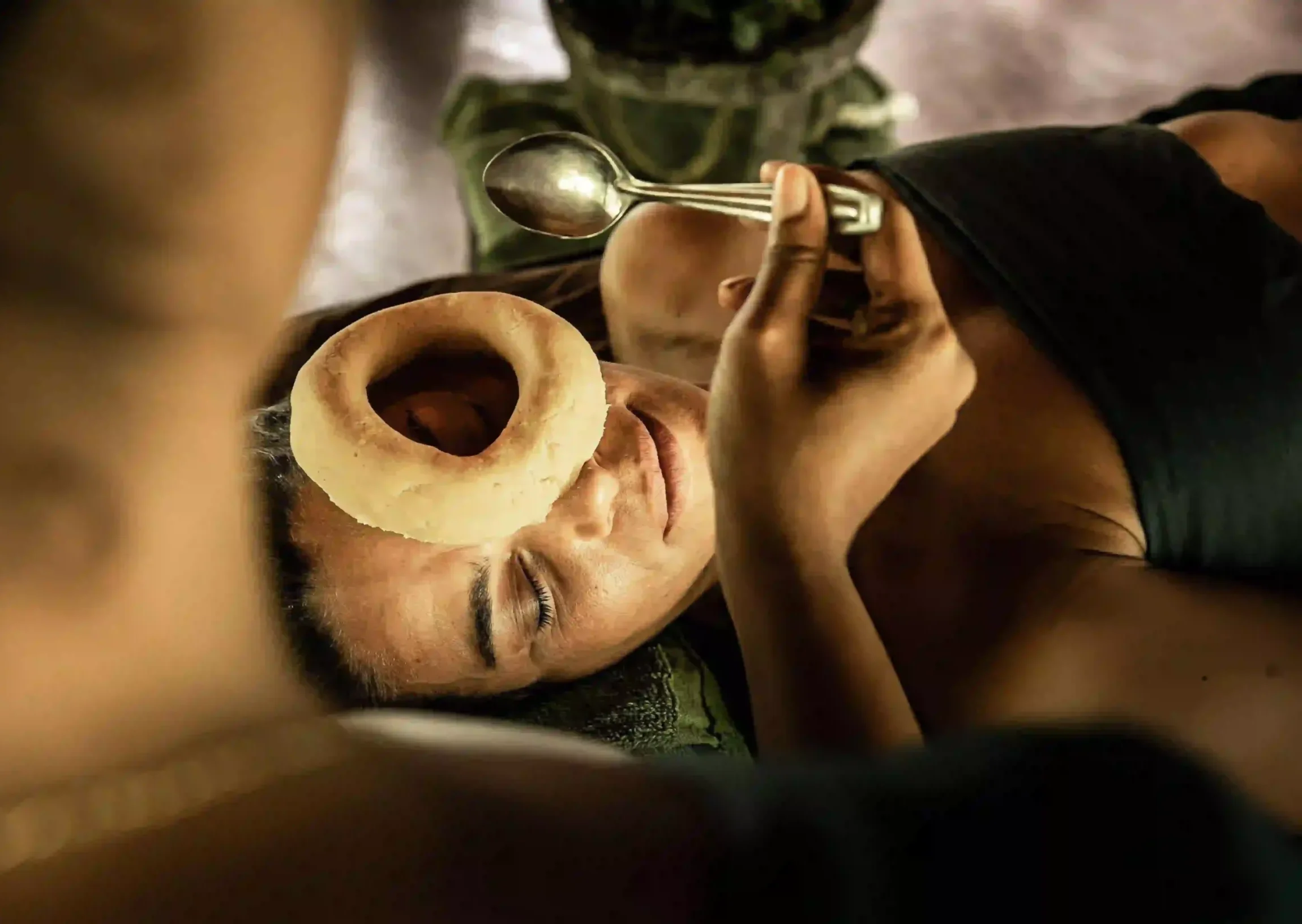 A woman receiving a traditional Ayurvedic Netra Tarpana eye therapy, where medicated ghee is gently applied around the eyes using a herbal dough ring, highlighting Ayurveda treatment for menopause and holistic wellness.